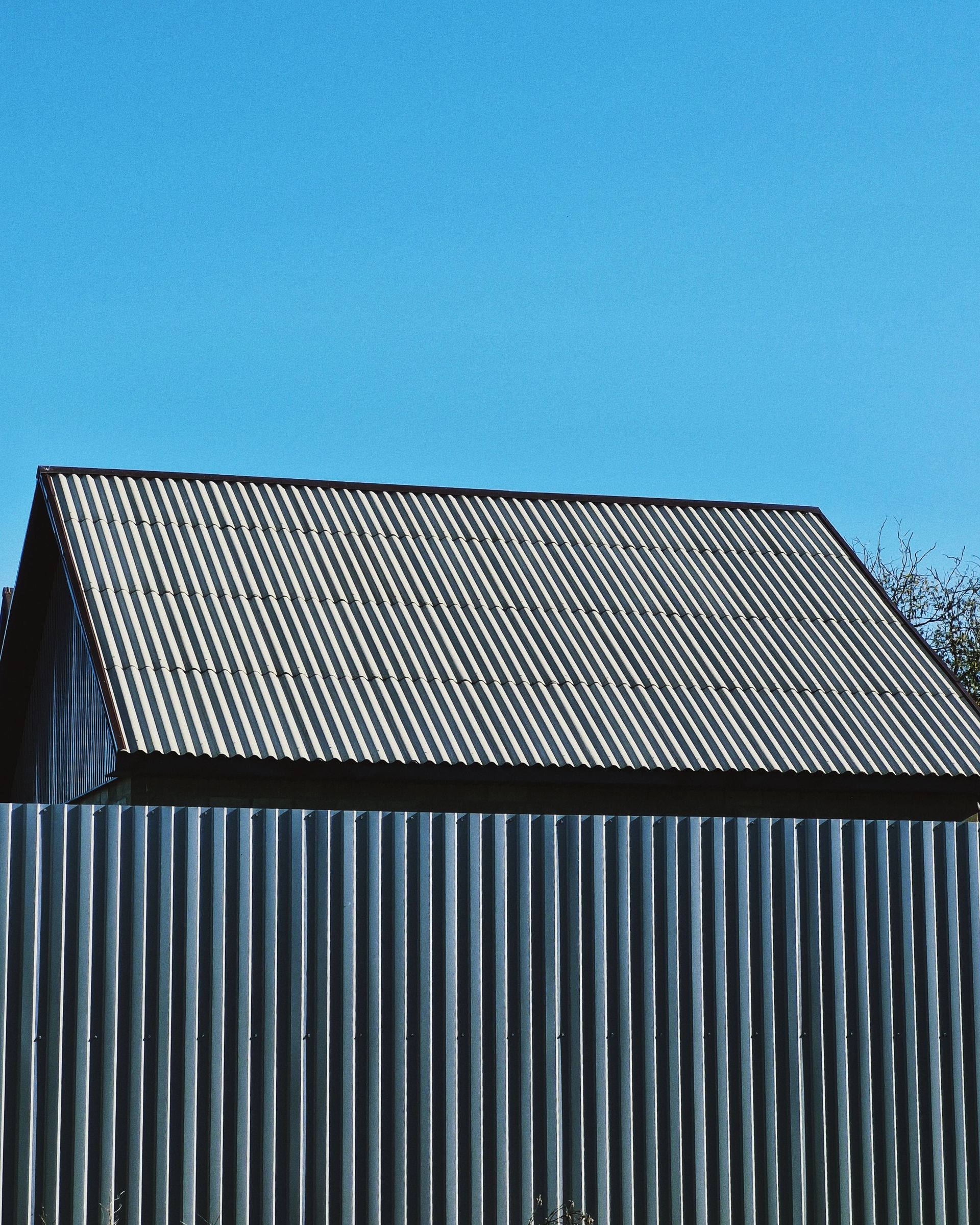 Minimalist photo of a corrugated metal roof with a clear blue sky background.