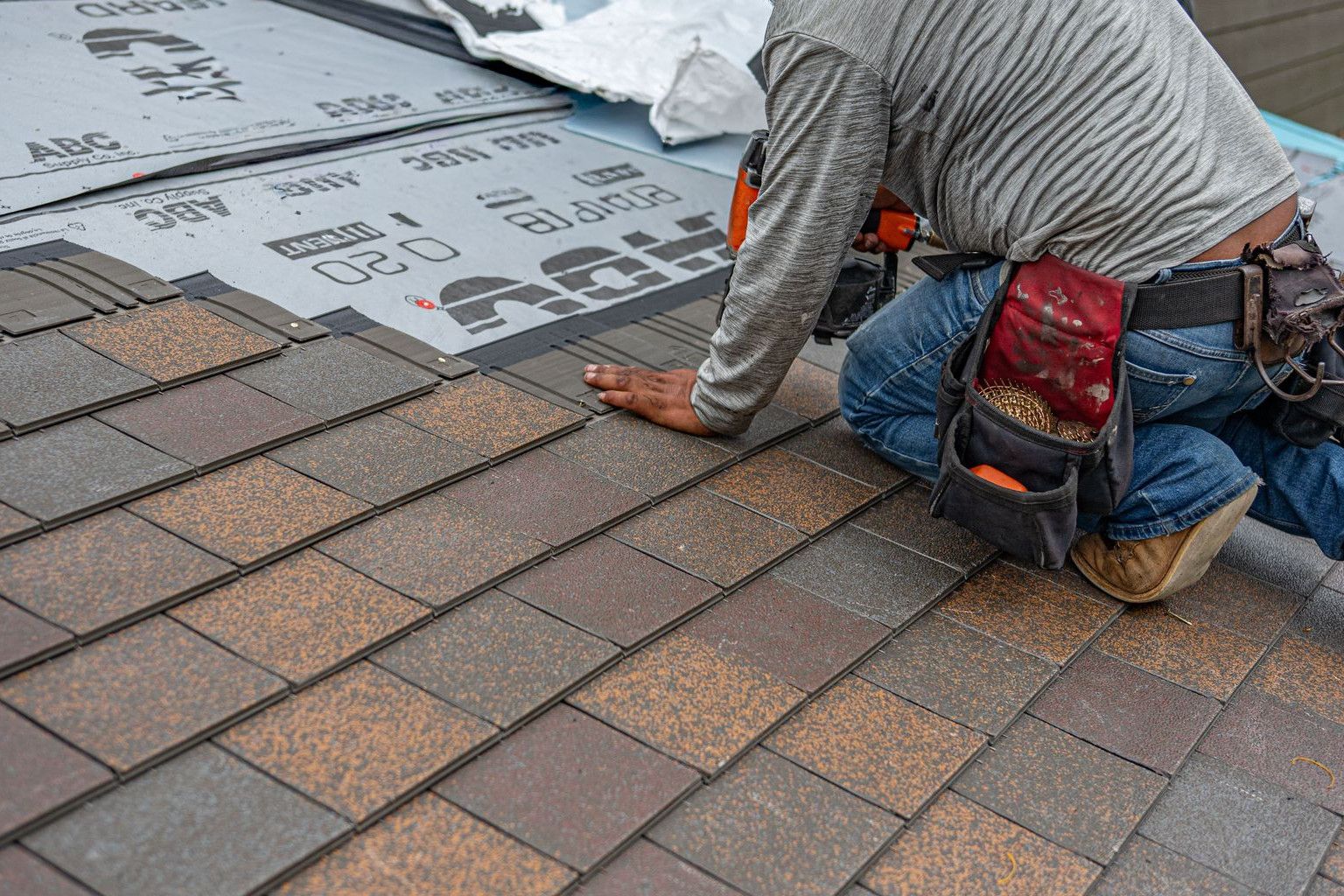 Skilled roofer installing asphalt shingles, ensuring quality home renovation.