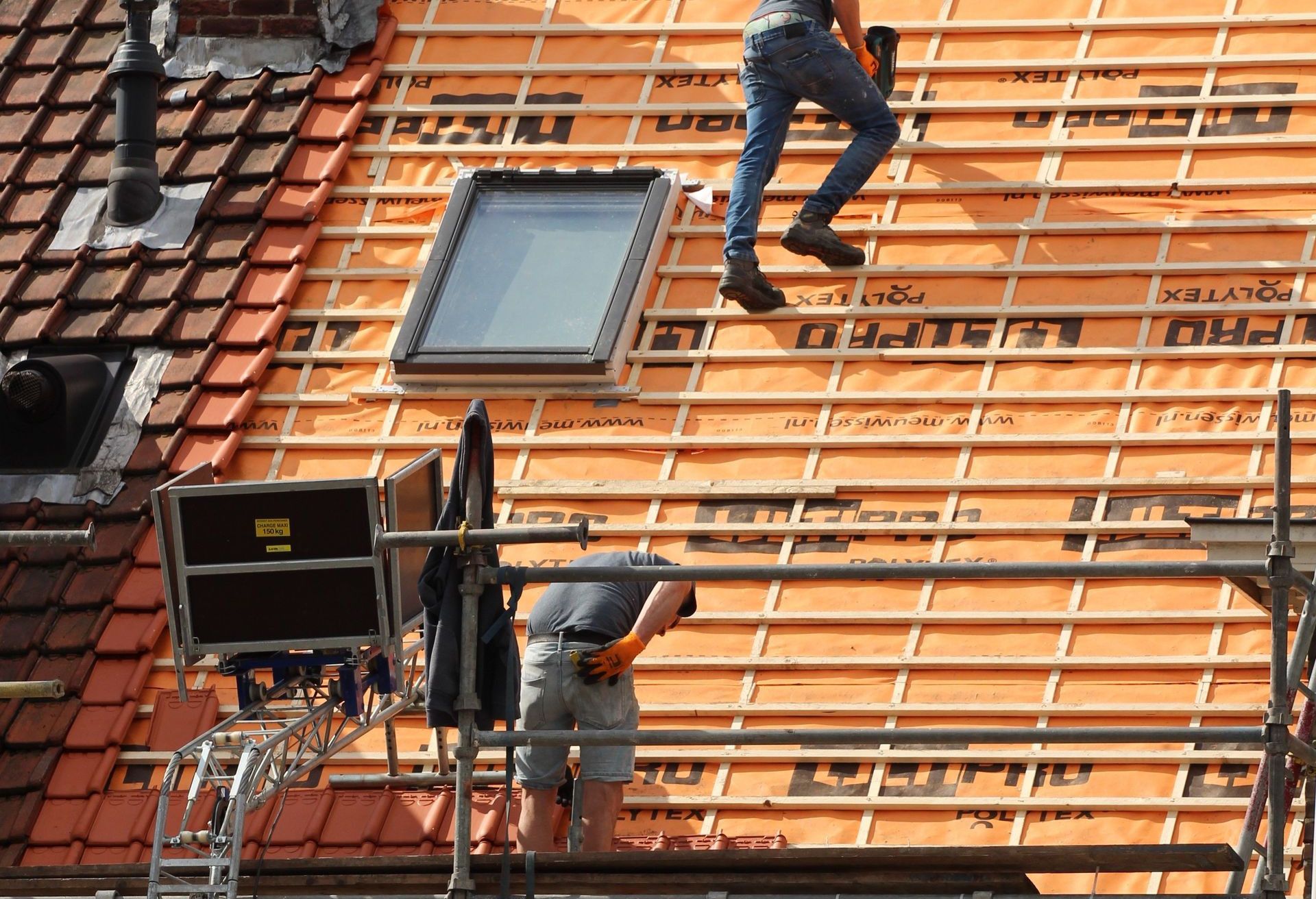 Construction workers installing new roof tiles in the Netherlands.