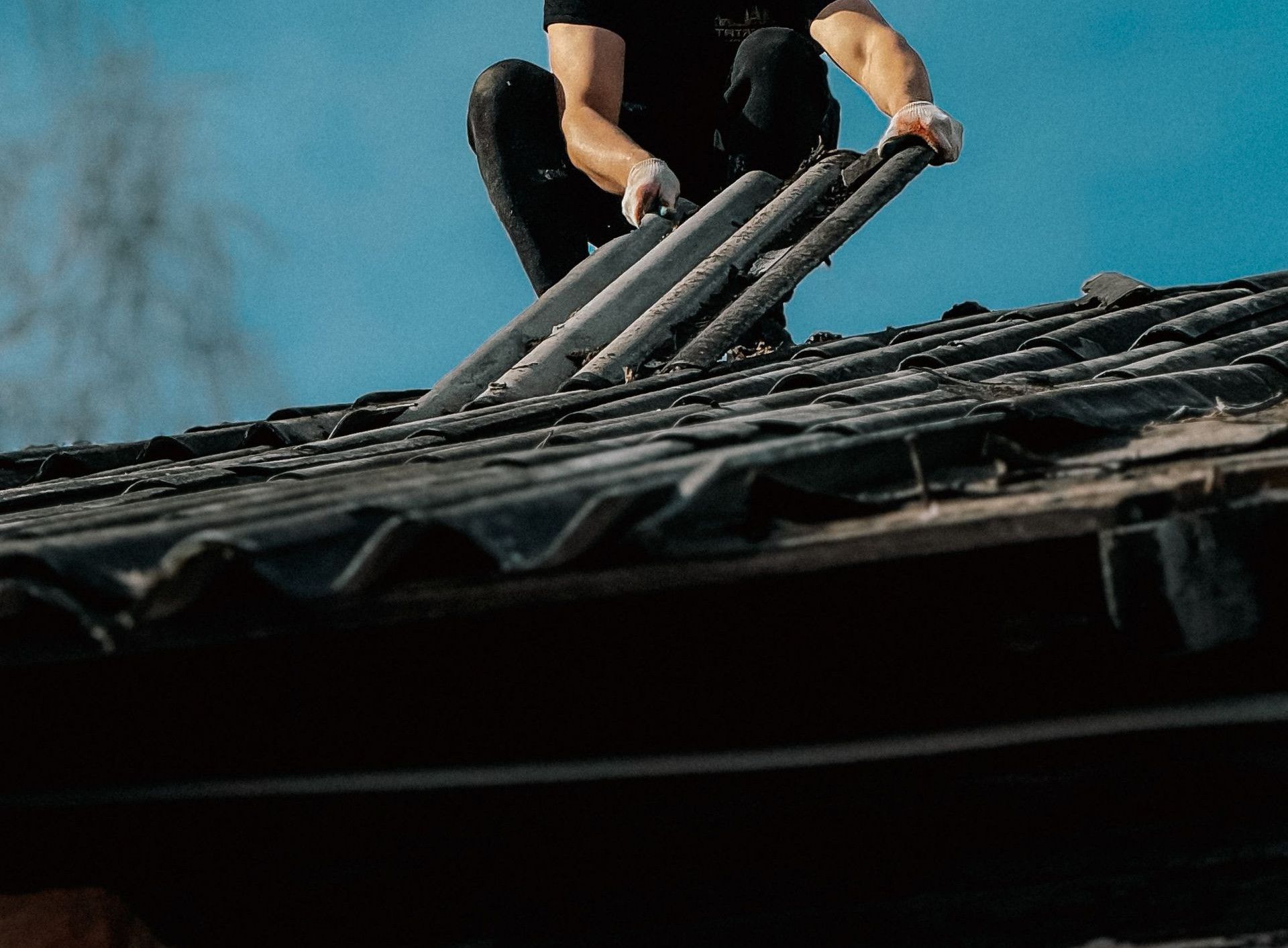 A man climbs a ladder onto a rooftop under a clear blue sky, focusing on safety and construction.
