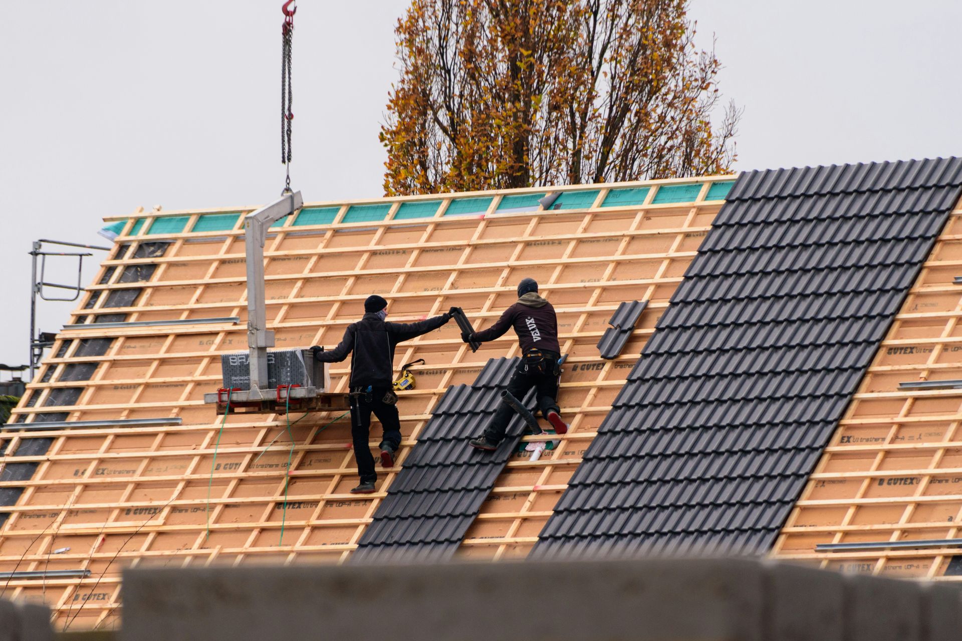 Workers installing roof tiles on a new building